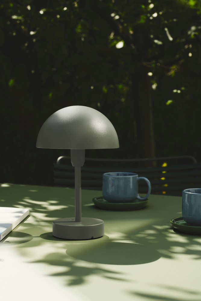 Schlichte Akkuleuchte Nordlux Ellen To-Go Oliven Grün auf dem Tisch neben zwei Tassen Tee