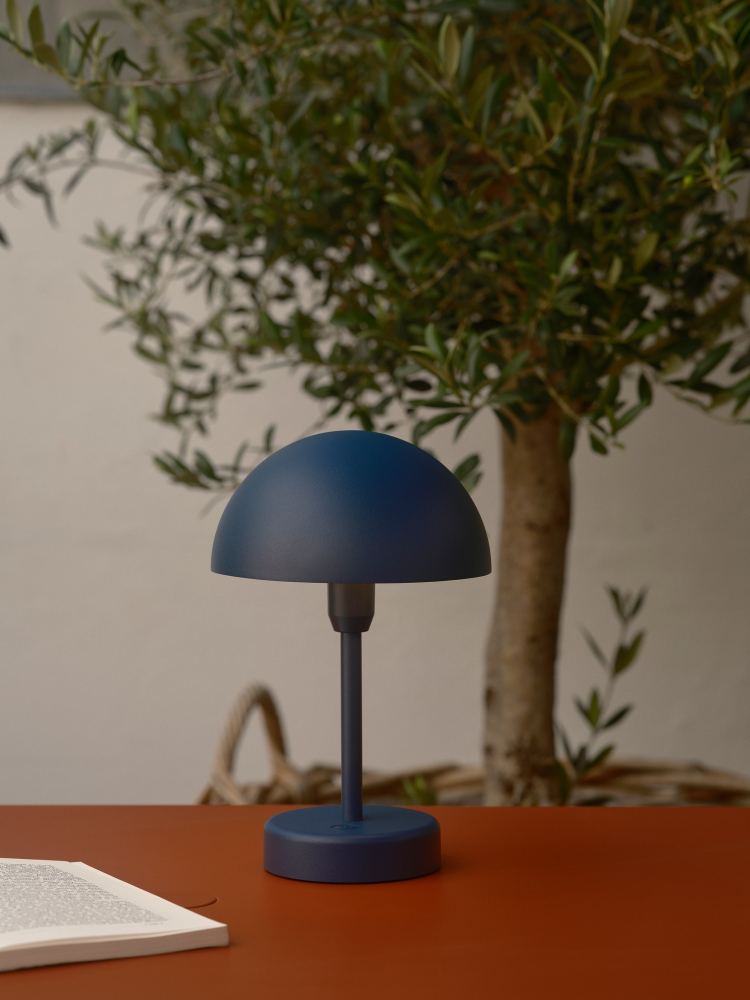 Oliven Grün Akkuleuchte Nordlux Ellen To-Go auf dem Tisch neben der Ladestation